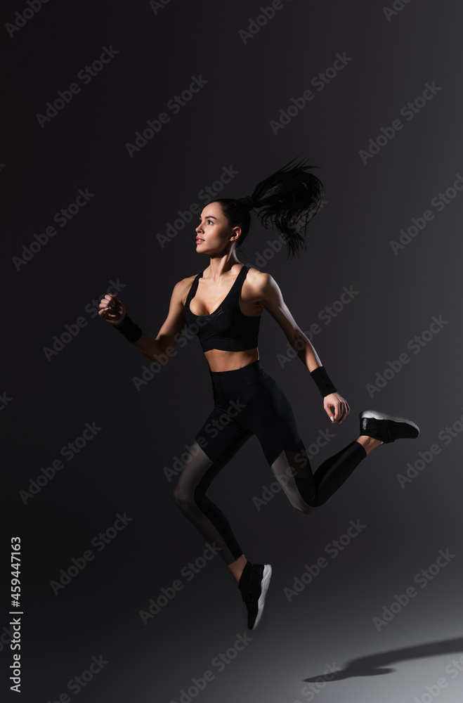 full length of sportive young woman flying on black
