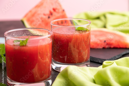 Watermelon juice with chia seeds and mint in glass on a black concrete background with green textile. Side view,  selective focus.