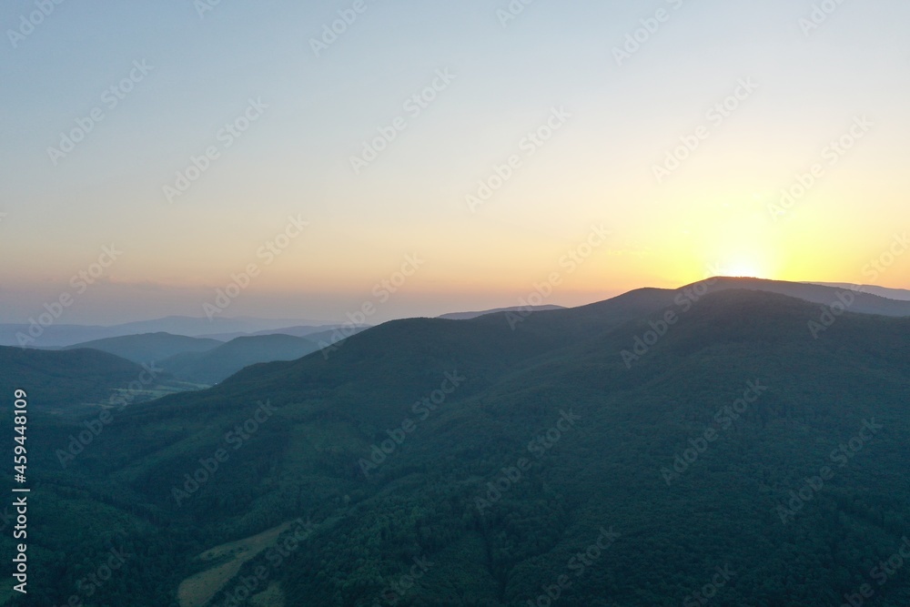 Peaks of the Carpathian Mountains at sunset. Sunset in the mountains, top view. Forest and mountains from a bird's eye view. Mountain range and valley.