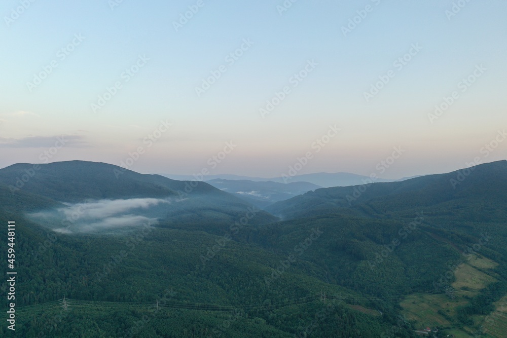 Obraz premium Peaks of the Carpathian Mountains at sunset. Sunset in the mountains, top view. Forest and mountains from a bird's eye view. Mountain range and valley.