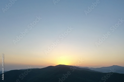 Peaks of the Carpathian Mountains at sunset. Sunset in the mountains, top view. Forest and mountains from a bird's eye view. Mountain range and valley. © Сергій Колесніков