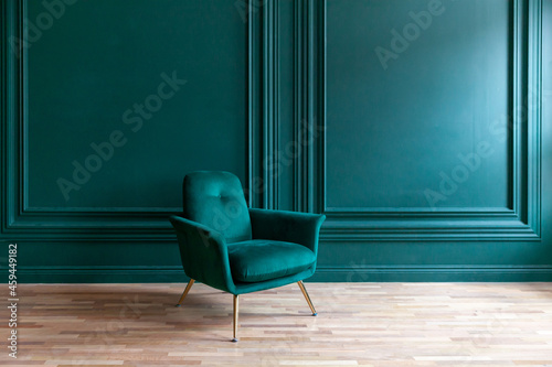 Beautiful luxury classic blue green clean interior room in classic style with green soft armchair. Vintage antique blue-green chair standing beside emerald wall. Minimalist home design.