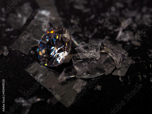 Close up shot of roud cut zircon zirconia gems with broken glass surrounded. Shoot on a black background.