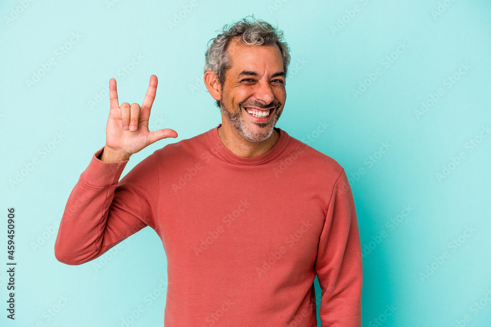 Middle age caucasian man isolated on blue background showing a horns gesture as a revolution concept. Middle age caucasian man isolated on blue background showing a horns gesture as a revolution concept.