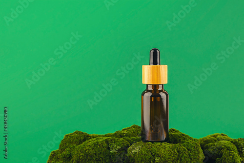 Amber glass dropper bottle with bamboo lid on green moss. Skincare products ,natural cosmetic. Beauty concept for face and body care