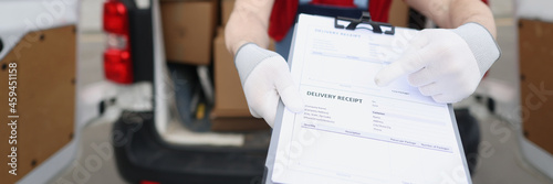 Male courier in protective mask pointing with finger where to sign on delivery receipt closeup © H_Ko