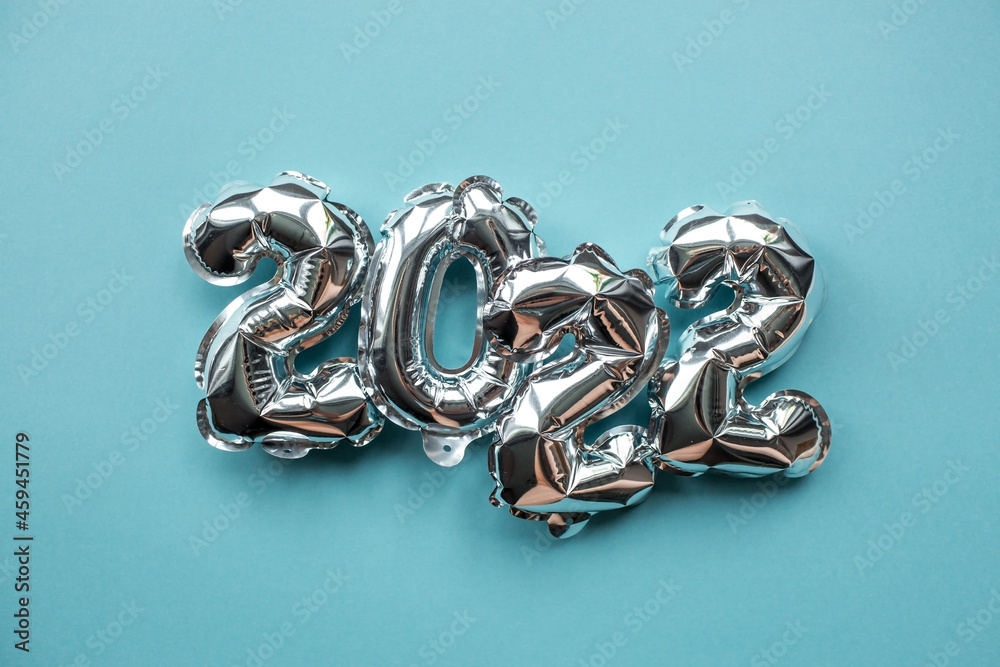 Banner. Happy New Year. Silver foil balloons with the number 2022 on a light blue background. Flat lay. Banner. Happy New Year. Silver foil balloons with the number 2022 on a light blue background. Flat lay.