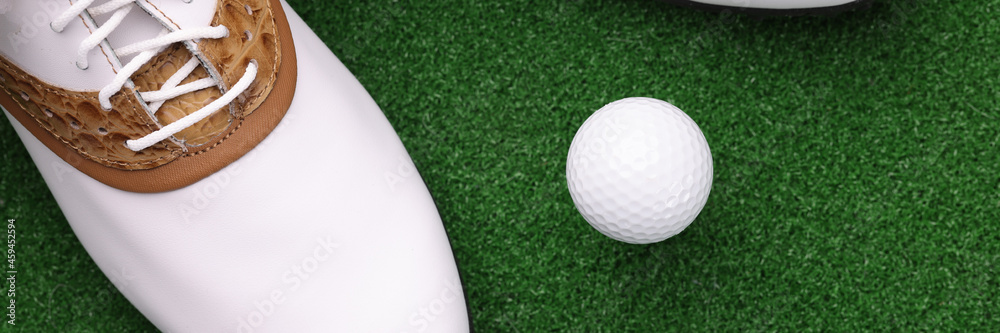 White shoes and ball lying on green golf course closeup White shoes and ball lying on green golf course closeup