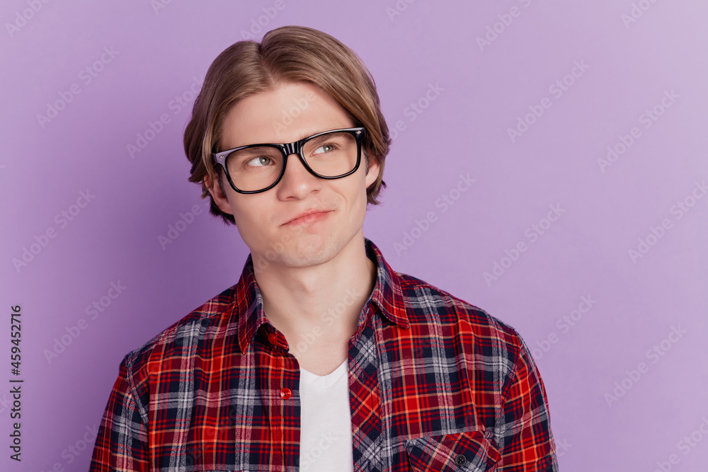 Portrait of interested minded intelligent guy look empty space unsure face on purple background