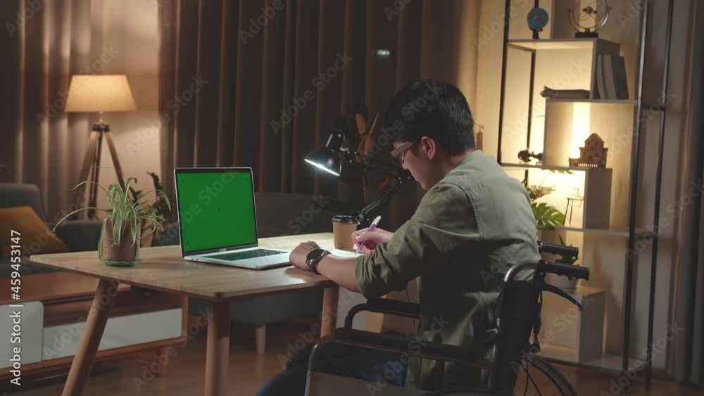 Asian Man Sitting In A Wheelchair While Working On Mock Up Green Screen Laptop Computer And Note In Book At Home, Night Time. Back View
Asian Man Sitting In A Wheelchair While Working On Mock Up Green Screen Laptop Computer And Note In Book At Home, Night Time. Back View