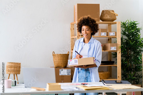 Smiling female entrepreneur writing on box while working at studio