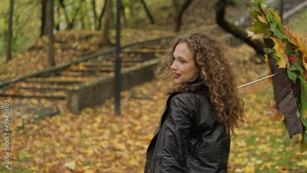 Positive woman whirling with umbrella from leaves in autumn park. Relax outdoors. Positive emotions. Caucasian woman laughs. Medium shot in 4K, UHD Positive woman whirling with umbrella from leaves in autumn park. Relax outdoors. Positive emotions. Caucasian woman laughs. Medium shot in 4K, UHD