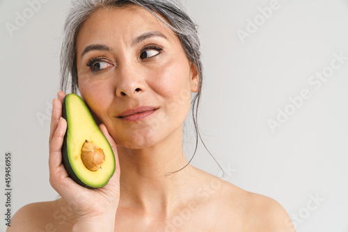 Mature shirtless woman with grey hair showing avocado