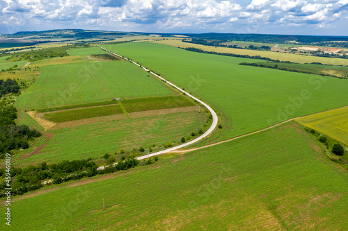 Amazing wide aerial view from drone of big road curve, countryside, fields, and cloudy sky