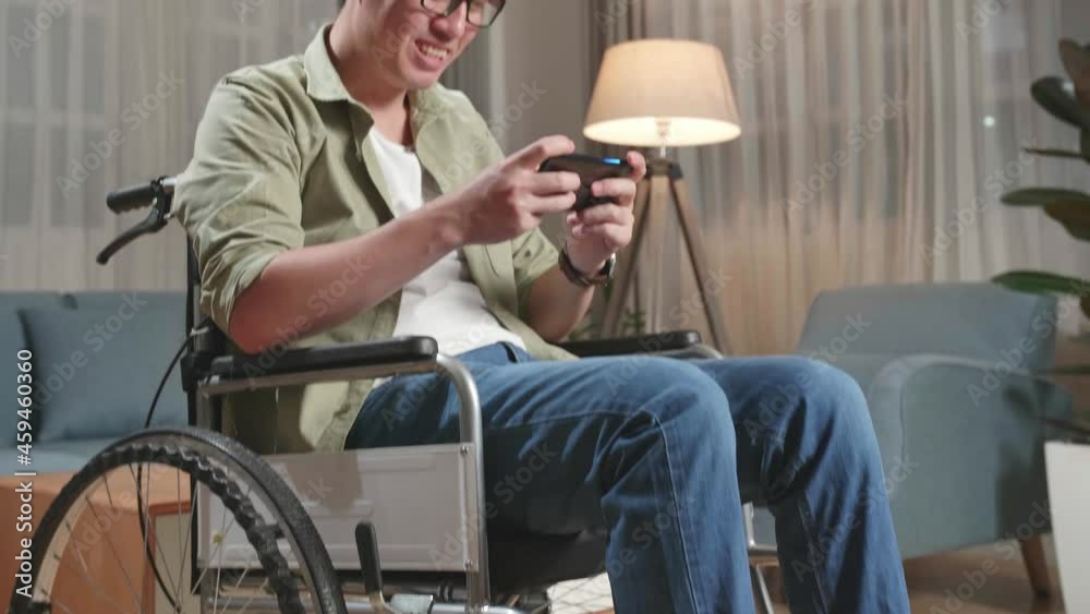 Happy Asian Man Sitting In A Wheelchair While Use Mobile Phone Playing Video Game And Celebrating At Home
Happy Asian Man Sitting In A Wheelchair While Use Mobile Phone Playing Video Game And Celebrating At Home