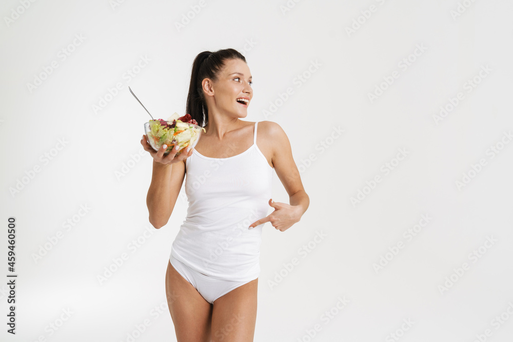 European woman pointing at her waist while posing with salad European woman pointing at her waist while posing with salad
