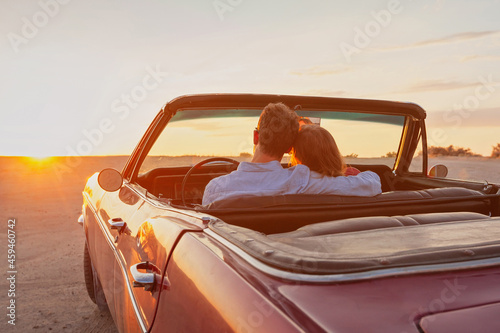 luxury, romantic couple in vintage classic cabriolet car at sunset photo