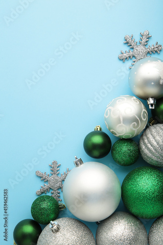 Christmas silver and green baubles on blue background. New Year composition