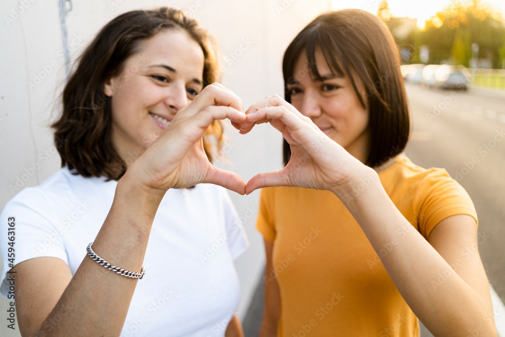 Young lesbian couple making heart with hands during sunset Young lesbian couple making heart with hands during sunset