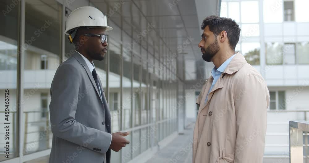 Businessman and engineer talk and shake hands outdoors Businessman and engineer talk and shake hands outdoors