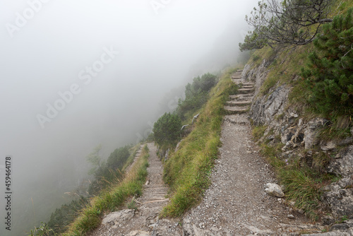 Foto Steep hiking path in the alps on cold autumn day with mist and fog