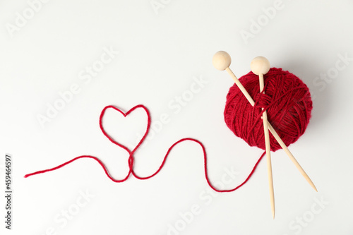 Red ball of yarn and knitting needles on white background