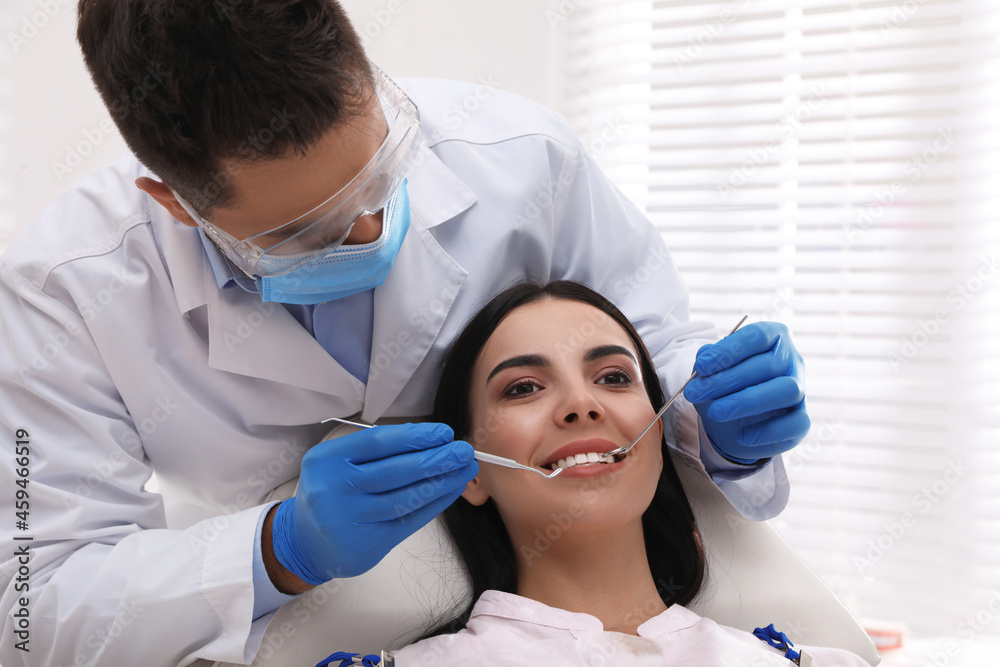 Dentist examining young woman's teeth in modern clinic Dentist examining young woman's teeth in modern clinic