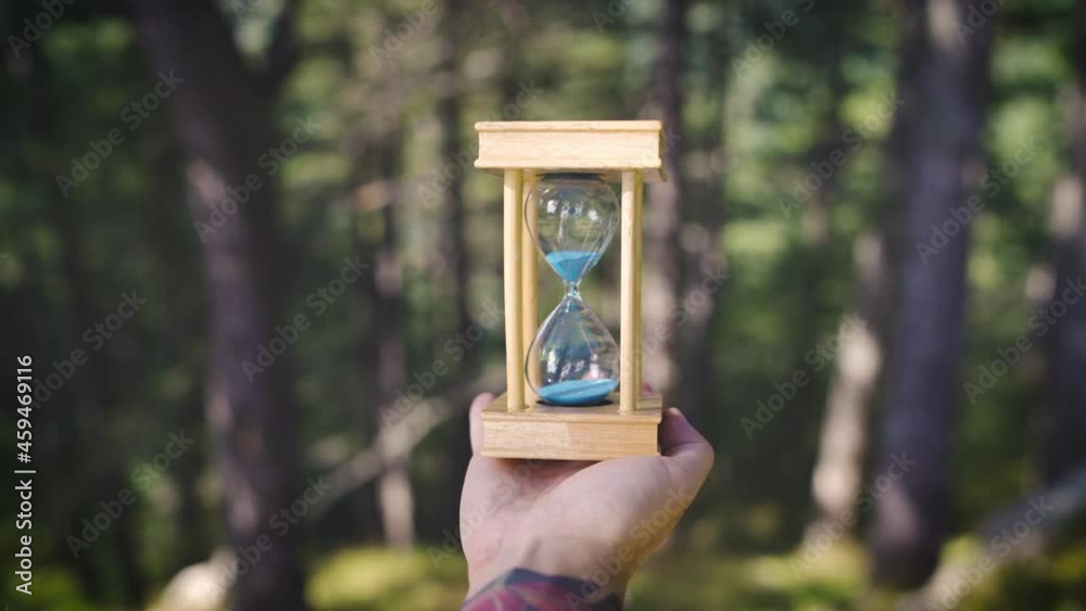 a man turns an hourglass in the forest fall back time concept pov