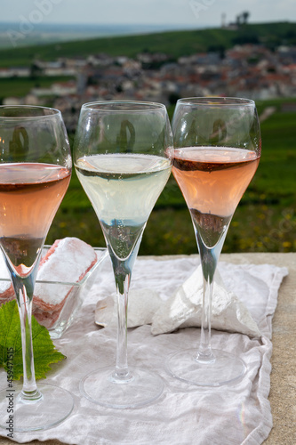 Glasses of white and rose brut champagne wine and examples of vineyard soils, white chalk stones and firestones and view on grand cru vineyards of  Montagne de Reims near Verzenay, Champagne, France