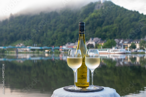 Tasting of white quality riesling wine served on outdoor terrace in Mosel wine region with Mosel river and old German town on background, Germany photo