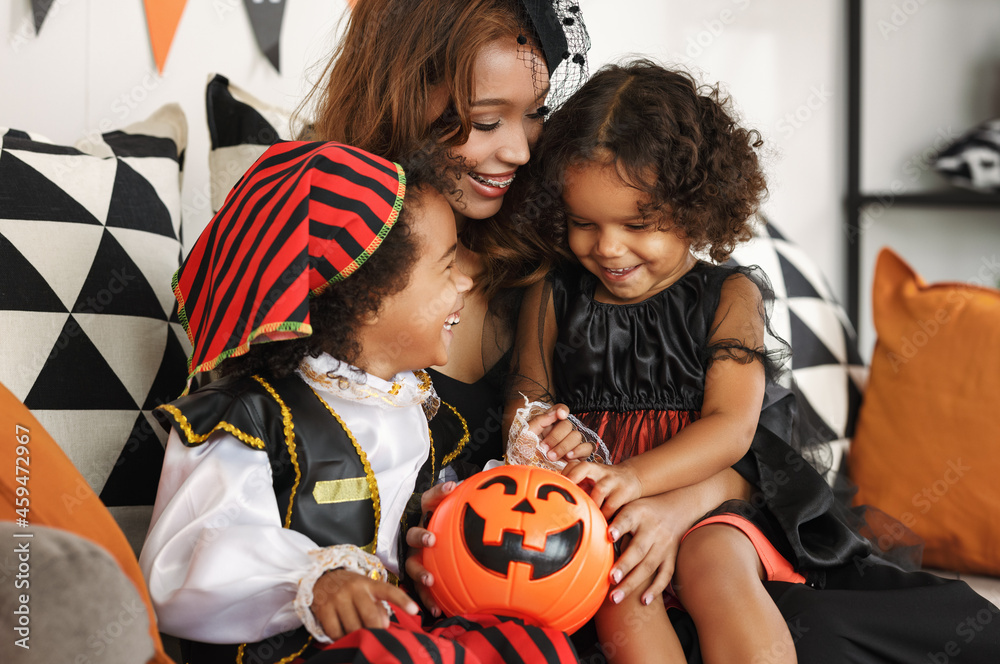 Happy african family in costumes celebrating Halloween holiday together at home Happy african family in costumes celebrating Halloween holiday together at home