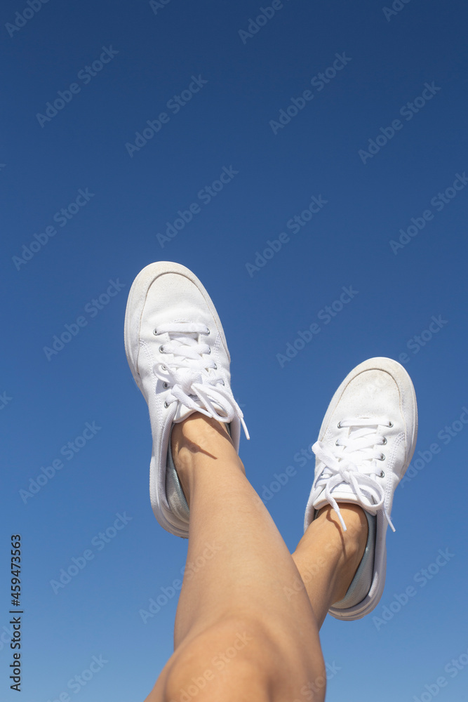 legs in sneakers on background of blue sky. legs in sneakers on background of blue sky.