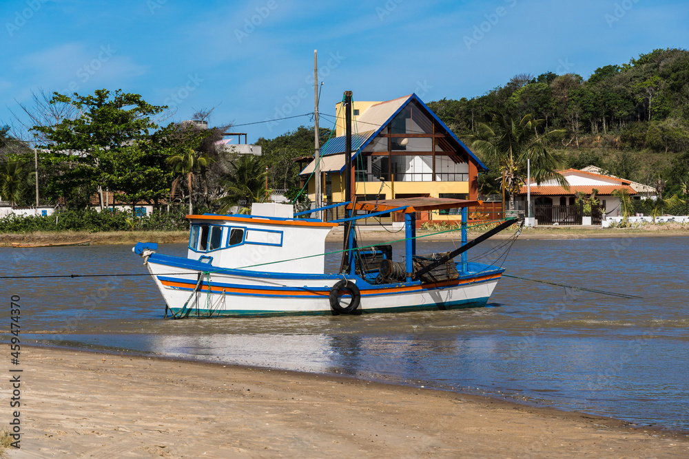 View of the beach of Rio das Ostras with the meeting of the river in Rio de Janeiro. Sunny day, blue sky. Yellow sand and some rocks. Wooden bridge to cross. Boats and fishing on the pier.