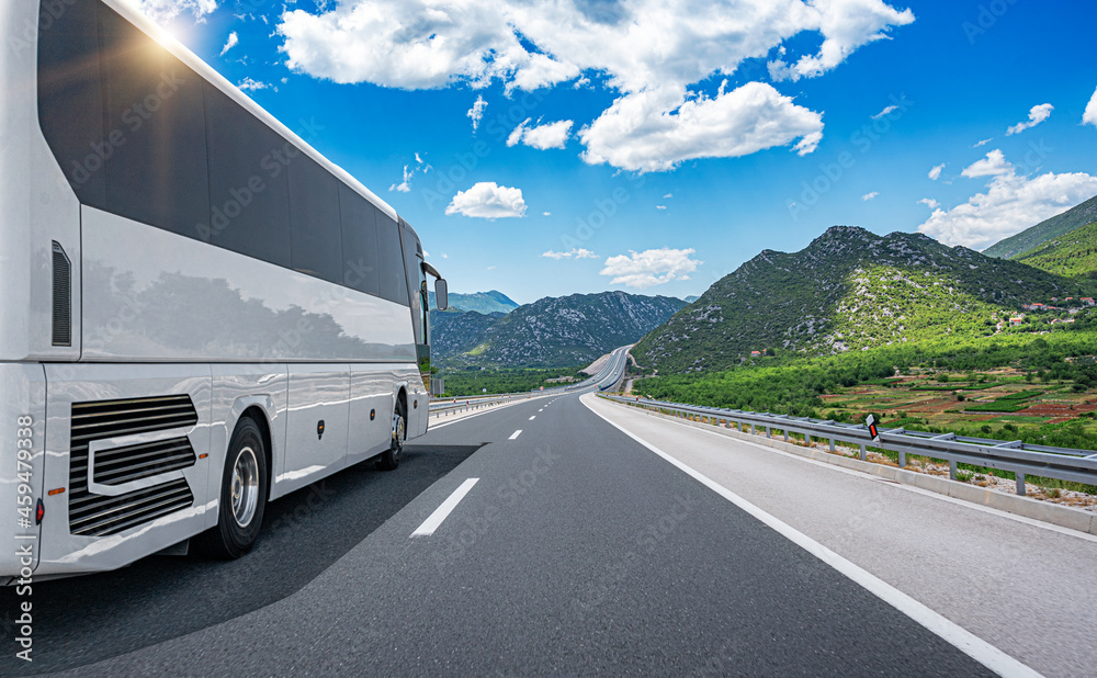 Obraz premium White passenger bus on the highway against the backdrop of a beautiful landscape.