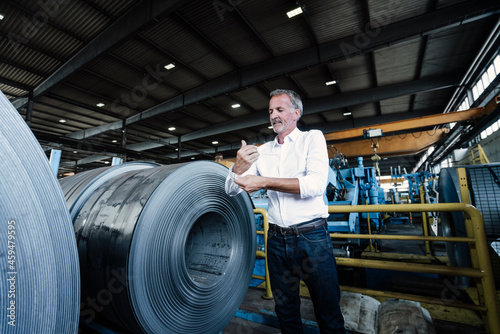 Senior businessman rolling sleeves while standing in steel mill photo