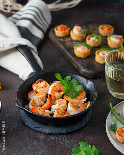 Fried shrimps prawns in a pan and croustades served on a white brown boards photo