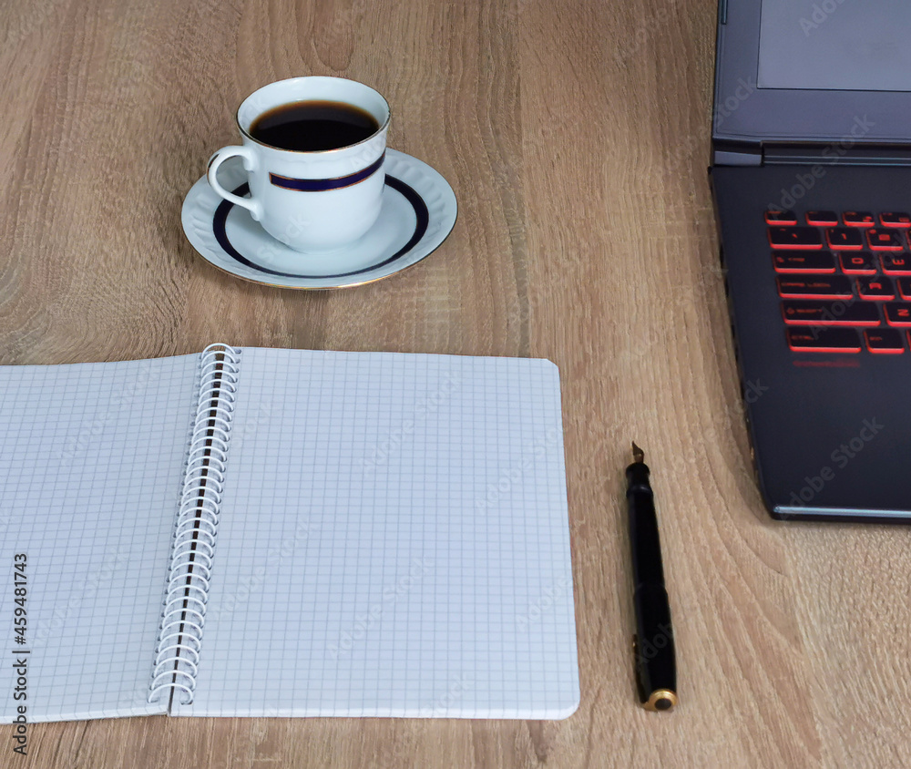 Close up cup of coffee, laptop computer, notebook and pen on wooden desk office. Workplace at home Close up cup of coffee, laptop computer, notebook and pen on wooden desk office. Workplace at home