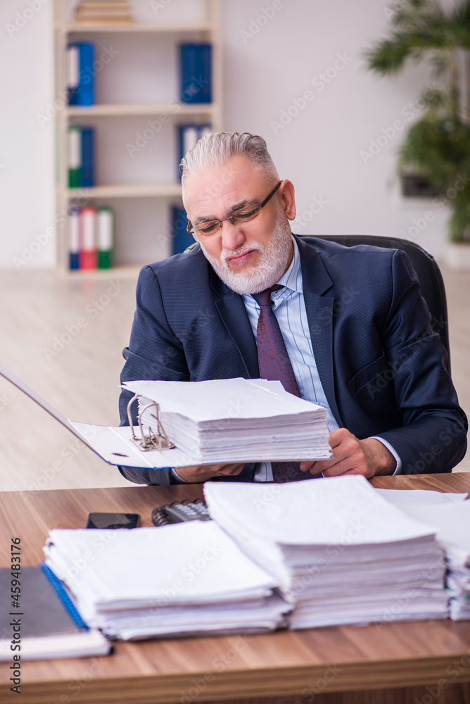 Old businessman employee unhappy with excessive work in the office