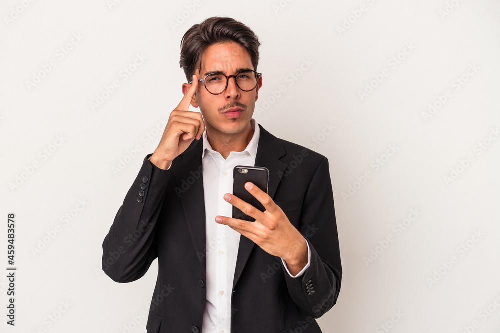 Young mixed race business man holding mobile phone isolated on white background pointing temple with finger, thinking, focused on a task. Young mixed race business man holding mobile phone isolated on white background pointing temple with finger, thinking, focused on a task.
