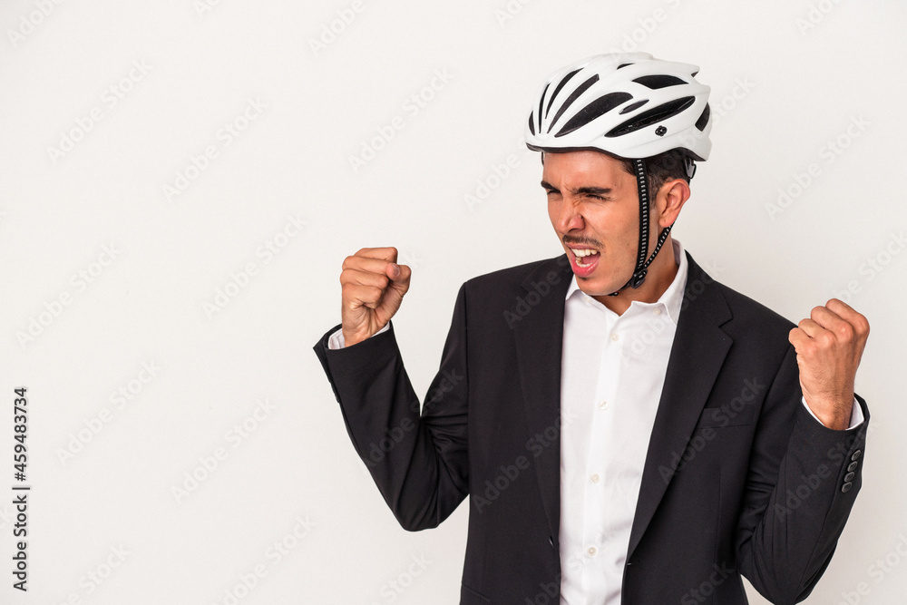 Young mixed race business man wearing a bike helmet isolated on white background raising fist after a victory, winner concept. Young mixed race business man wearing a bike helmet isolated on white background raising fist after a victory, winner concept.