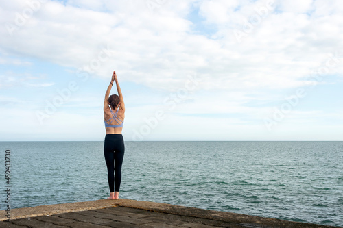Yoga poses, woman doing tadasana by the sea. photo