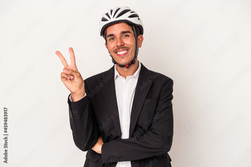 Young mixed race business man wearing a bike helmet isolated on white background joyful and carefree showing a peace symbol with fingers. Young mixed race business man wearing a bike helmet isolated on white background joyful and carefree showing a peace symbol with fingers.