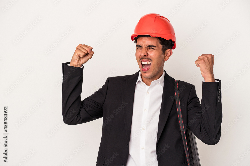 Young architect mixed race man isolated on white background raising fist after a victory, winner concept. Young architect mixed race man isolated on white background raising fist after a victory, winner concept.