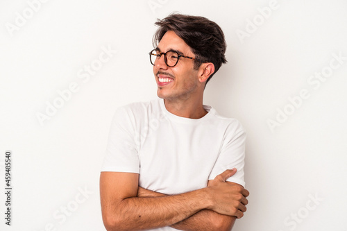 Young mixed race man isolated on white background smiling confident with crossed arms. © Asier