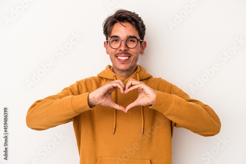 Young mixed race man isolated on white background smiling and showing a heart shape with hands.