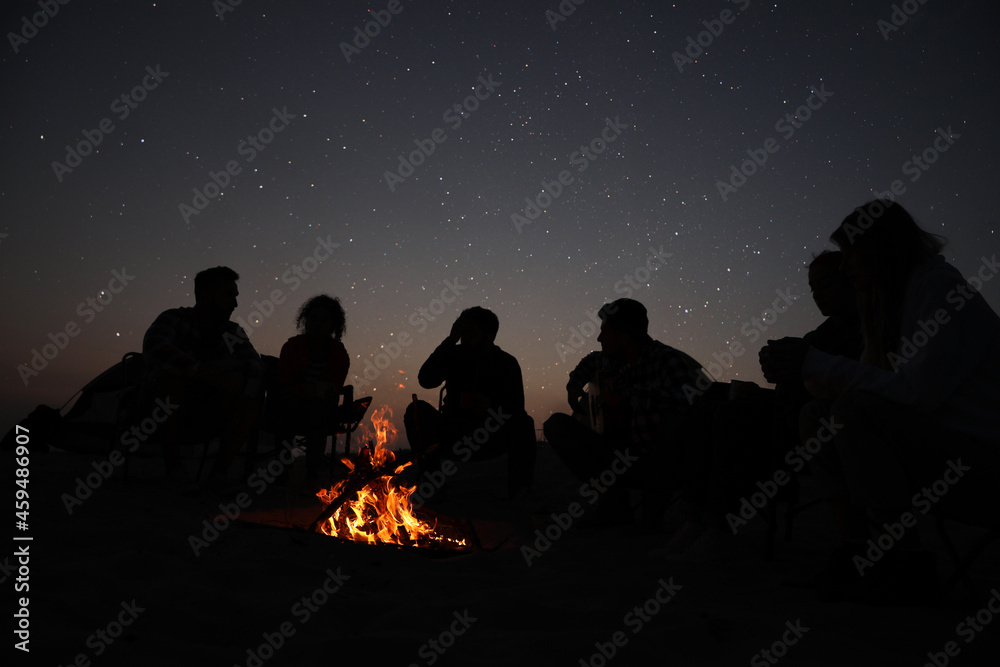 Group of friends gathering around bonfire in evening. Camping season Group of friends gathering around bonfire in evening. Camping season