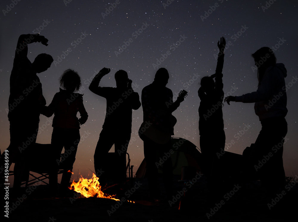 Group of friends having party near bonfire in evening. Camping season Group of friends having party near bonfire in evening. Camping season