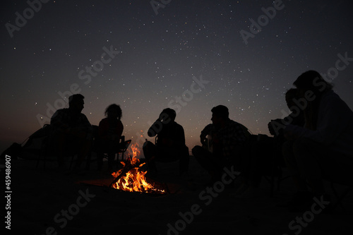 Canvas-taulu Group of friends gathering around bonfire in evening