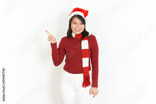 Pointing and presenting product aside of Beautiful Asian Woman Wearing Red Turtleneck and Santa Hat Isolated On White Background