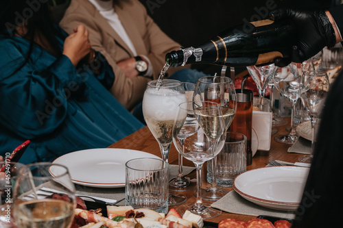 Elegant waiter pours champagne from bottle into glass at restaurant. Sommelier tasting white sparkling wine in restaurant. Copy space for text menu elegant or recipe on dark background.